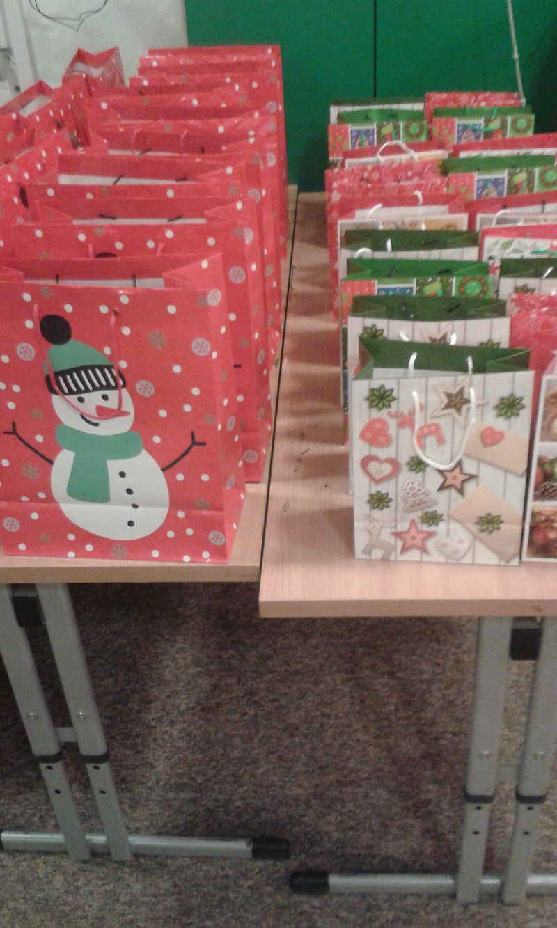 stolik na którym ustawione są w rzędach świąteczne torebki z prezentami dla zuchów i harcerzy