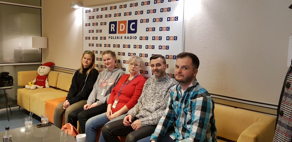 dyrektor szkoły, nauczyciel języka angielskiego i dwie uczennice siedzą wraz z redaktorką na kanapie