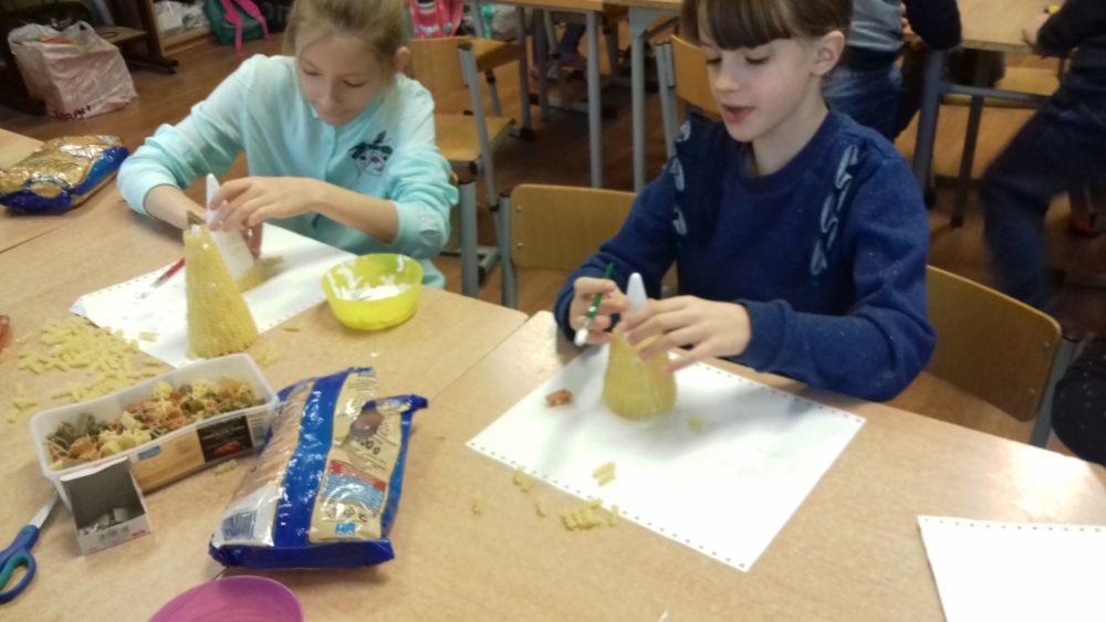 Dzieci oklejają stożki styropianowe makaronem
