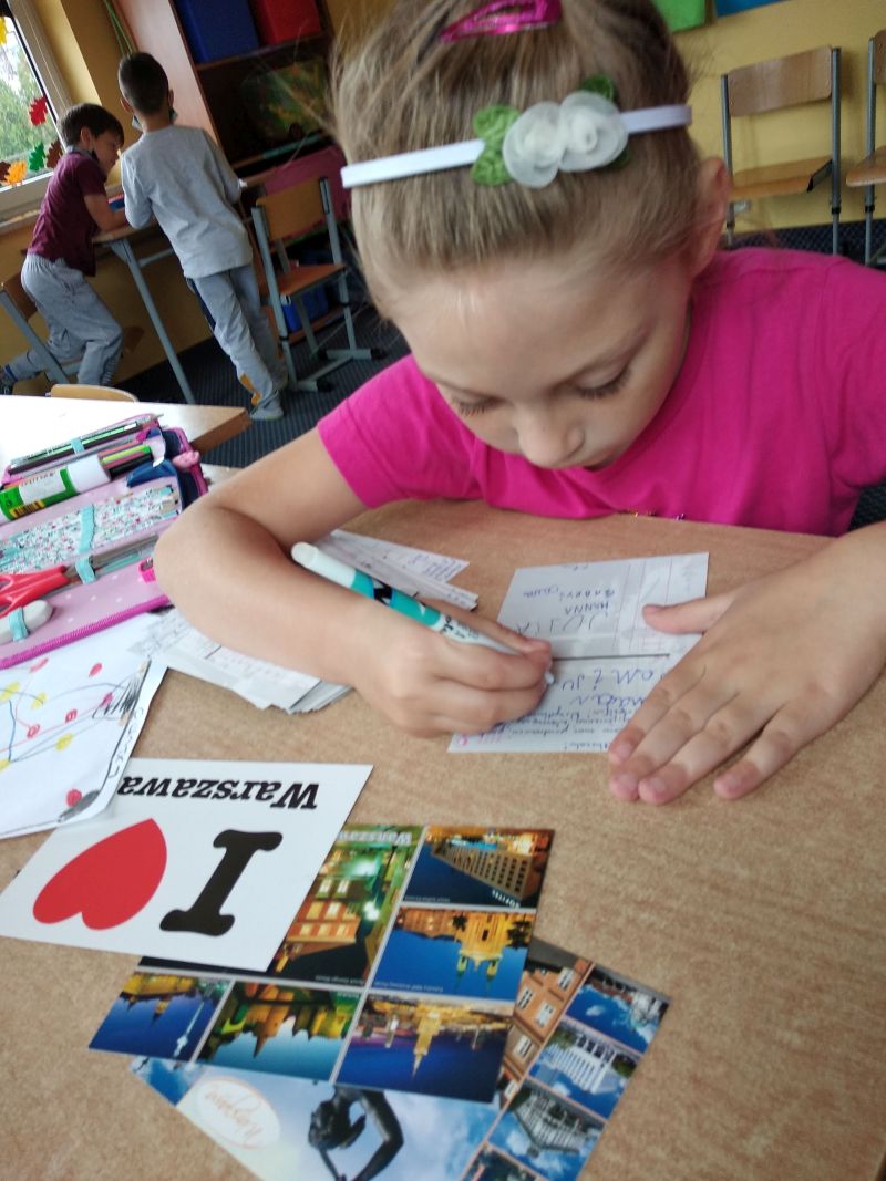 dziewczynka podpisuje sie na pocztówce