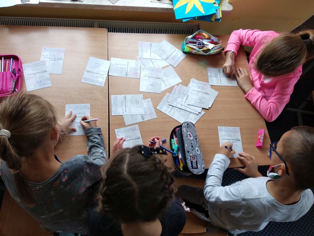 uczniowie podpisują pcoztówki