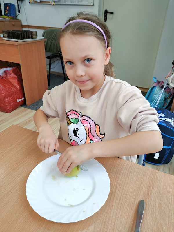 zdjęcie przedstawia dziewczynkę krojącą jabłko