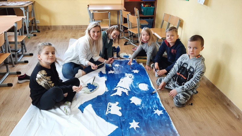 Uczniowie malujący na płótnie krajobraz zimowy