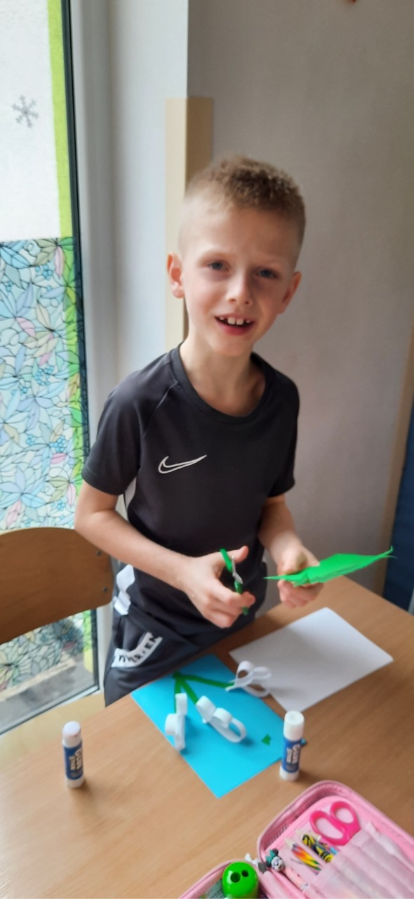 chłopiec podczas wycinania liści z kolorowego papieru.