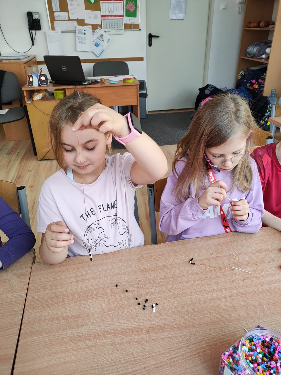 zdjęcie przedstawia dziewczynki wykonujące bransoletki