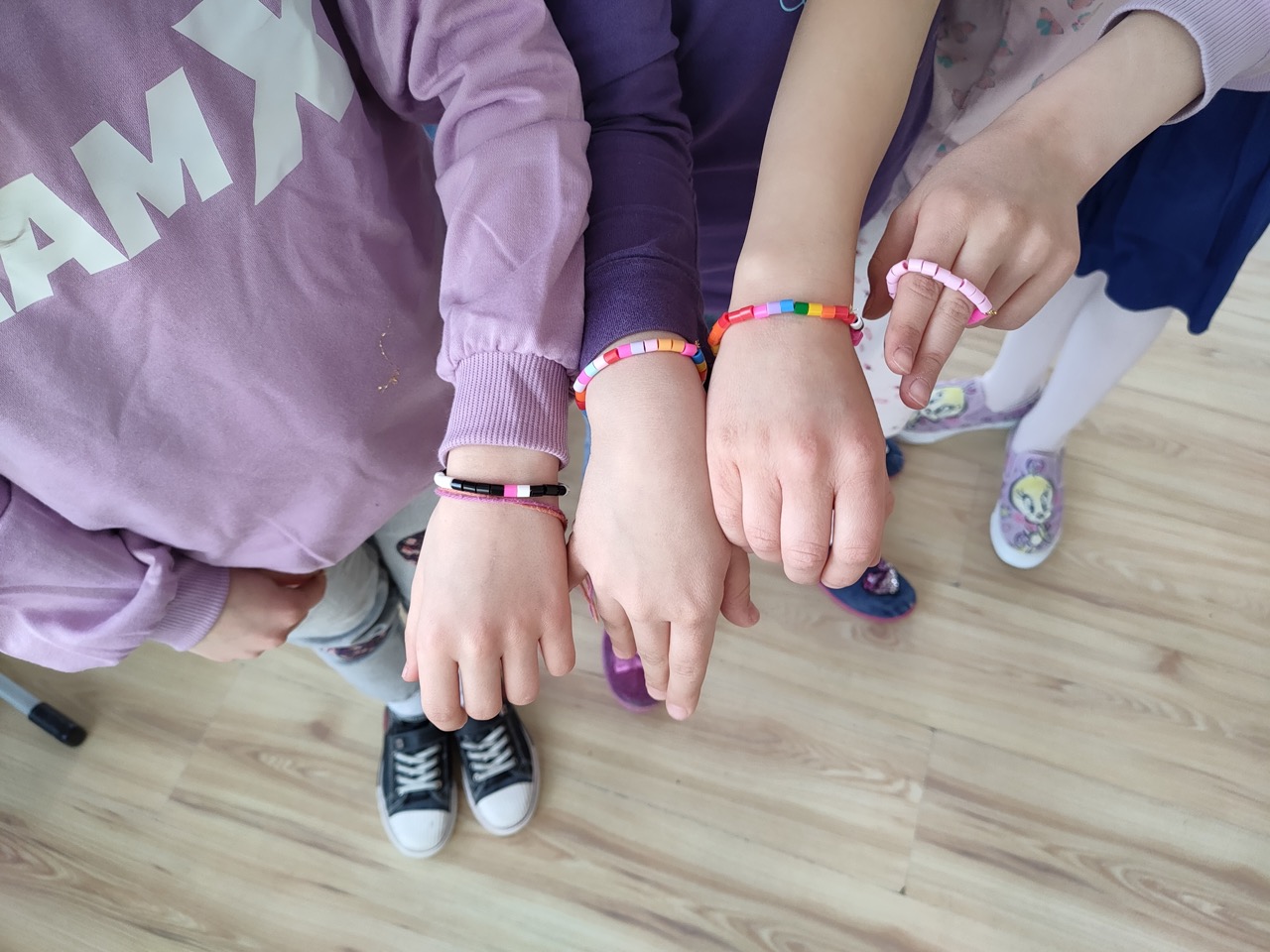 zdjęcie przedstawia ręce dzieci z kolorowymi bransoletkami