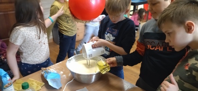 Zdjęcie przedstawia uczniów, którzy ucierają mikserem ciasto na gofry