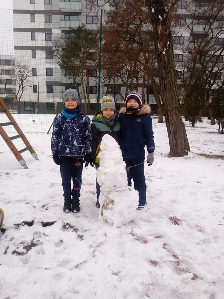 chłopcy pozują na tle ulepionego bałwana 