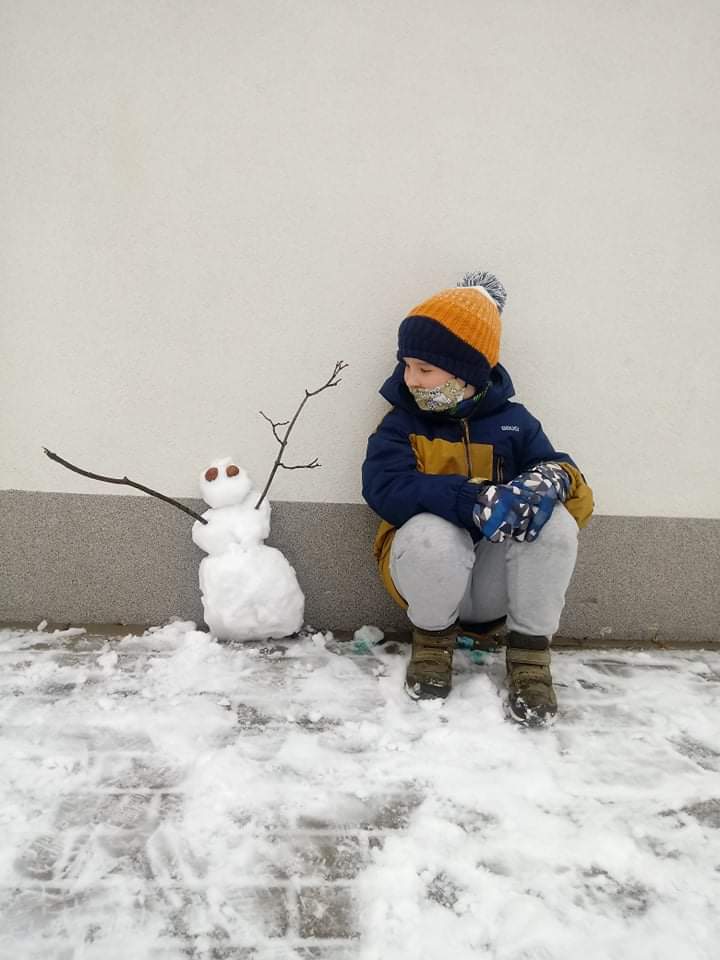 chłopiec pokazuje ulepionego przez siebie bałwana 