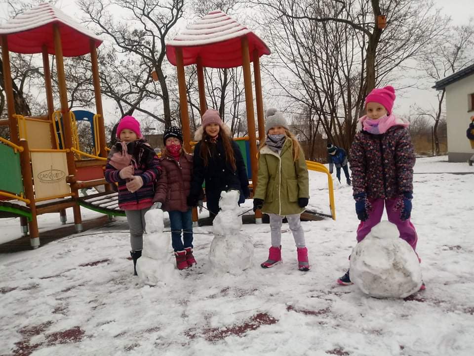 dziewczynki pokazują ulepione przez siebie bałwany 