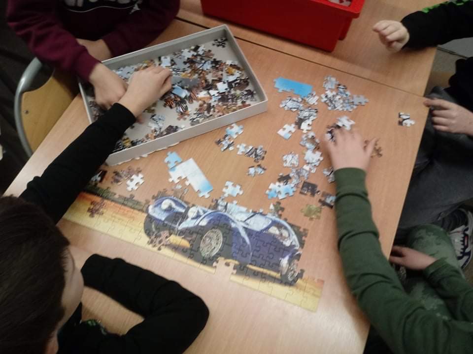 dzieci układają puzzle z obrazkiem samochodu