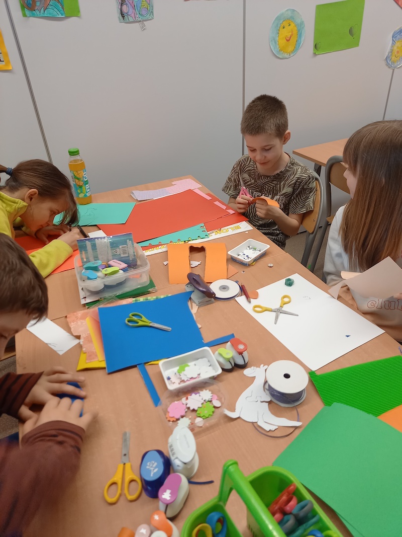 dzieci wykonują zakładki do książek z papieru kolorowego i różnych materiałów 