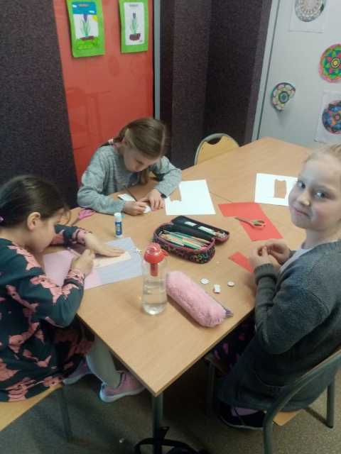 dzieci wykonują zakładki do książek z papieru kolorowego i różnych materiałów 