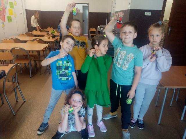 dzieci prezentują wykonane przez siebie zawieszki w kształcie sowy 