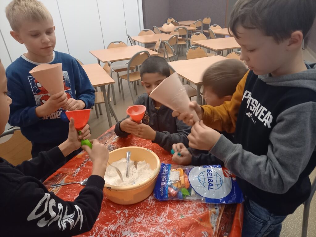 chłopcy wykonują gniotki z balonów – napełniają balony mąką