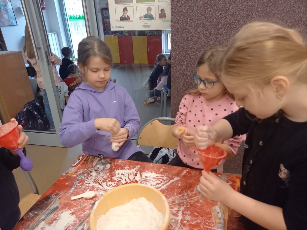 dziewczynki wykonują gniotki z balonów – napełniają balony mąką