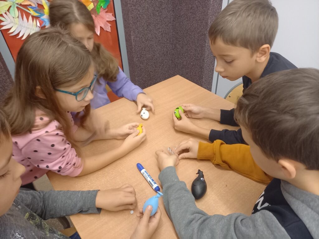 dzieci ozdabiają flamastrami wykonane gniotki, przyklejają Oczki plastikowe