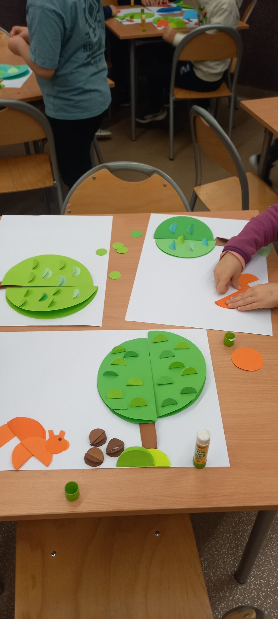 dzieci wykonują pracę z papieru kolorowego - jesień - drzewo, wiewiórkę - origami płaskie kółko