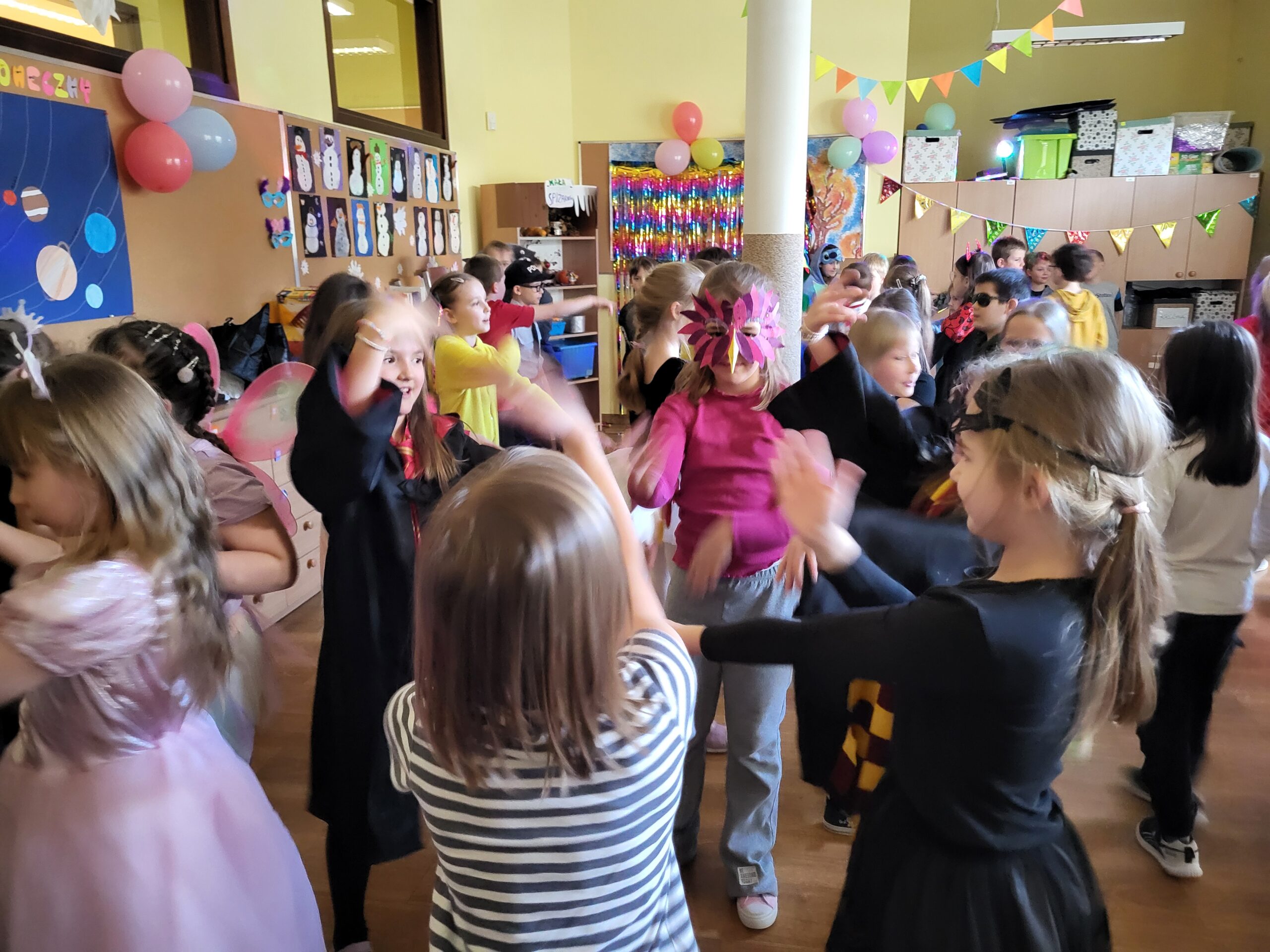 Na zdjęciu widać grupę dzieci w strojach karnawałowych i przebraniach wspólnie tańczących