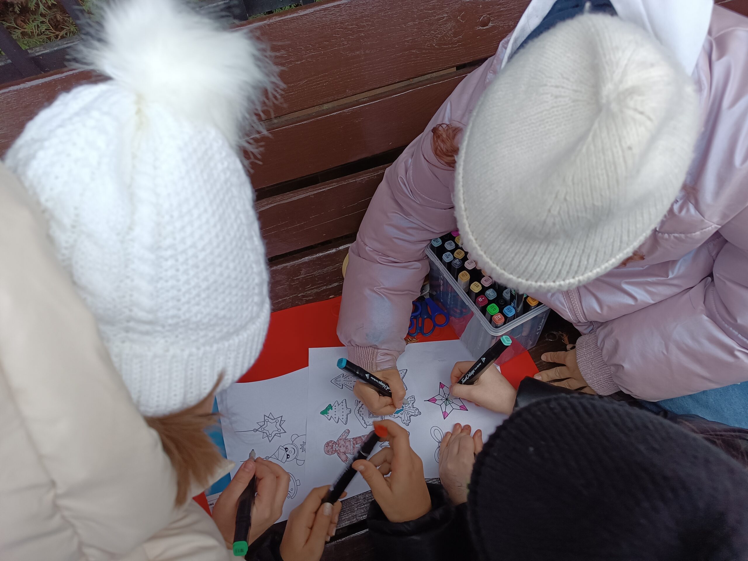 Na zdjęciu widać dzieci kolorujące dekoracje bożonarodzeniowe