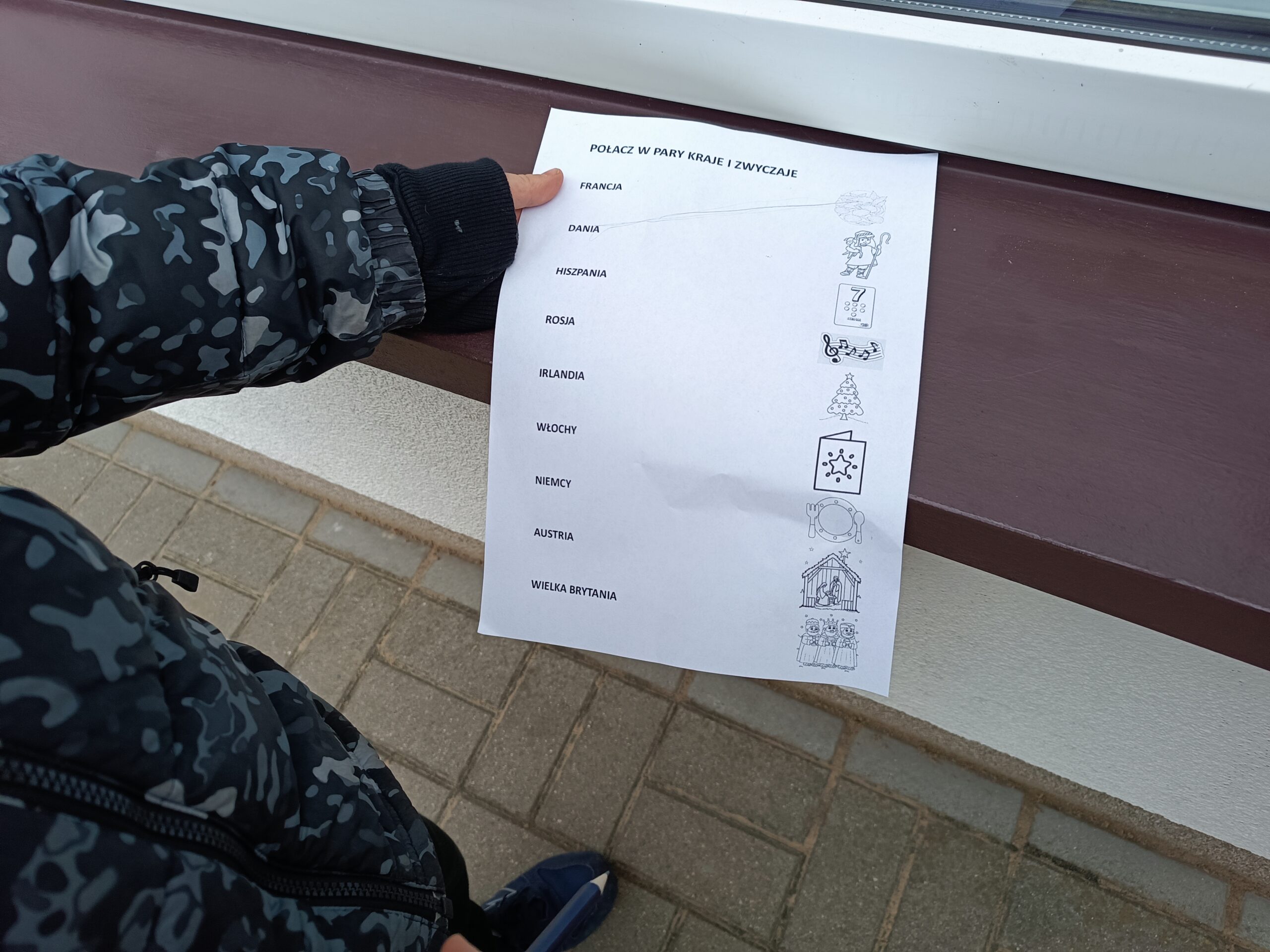 Na zdjęciu widać kartę z jednym z zadań do wykonania podczas gry polegającą na połączeniu w pary nazw państw z obrazkami symbolizującymi zwyczaje bożonarodzeniowe