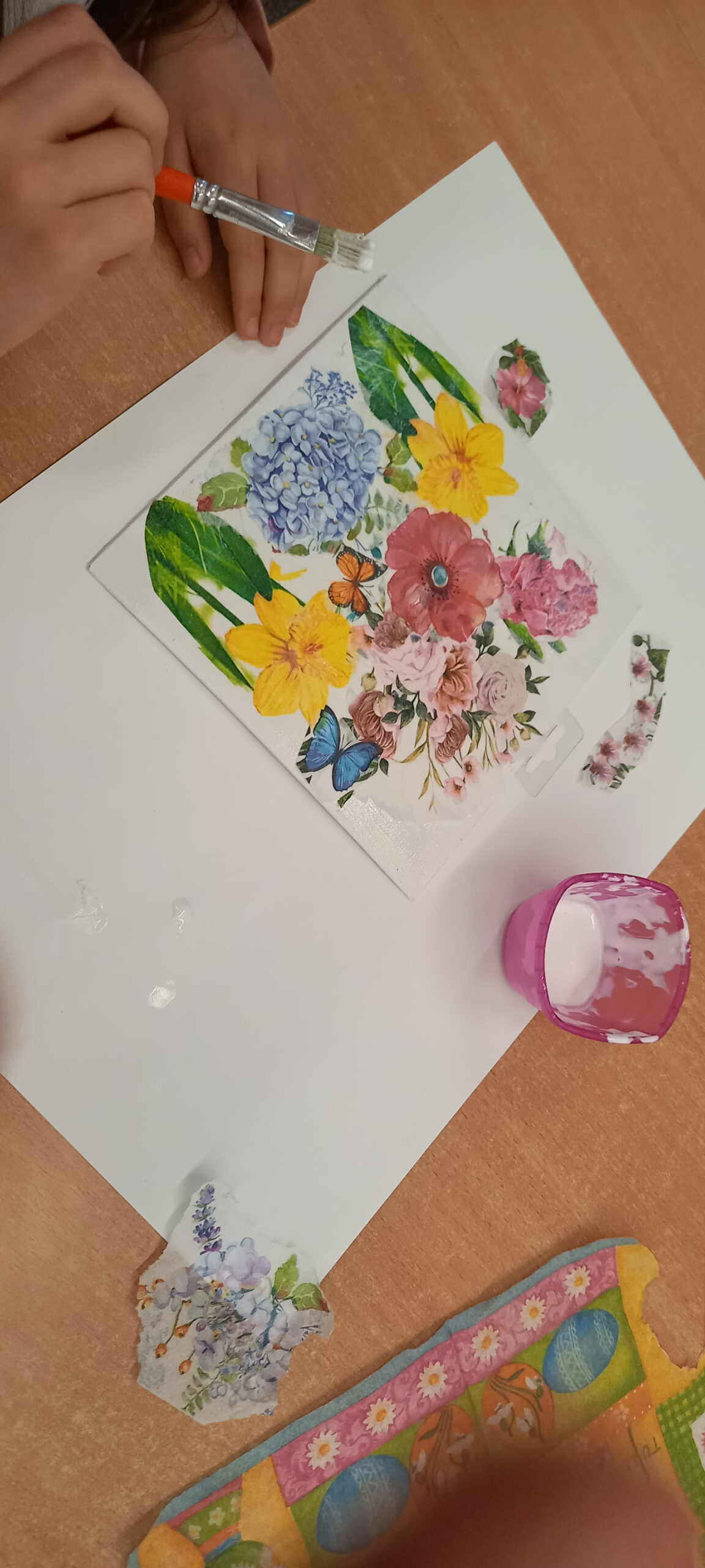 dziewczynka wykonuje obrazek techniką decoupage