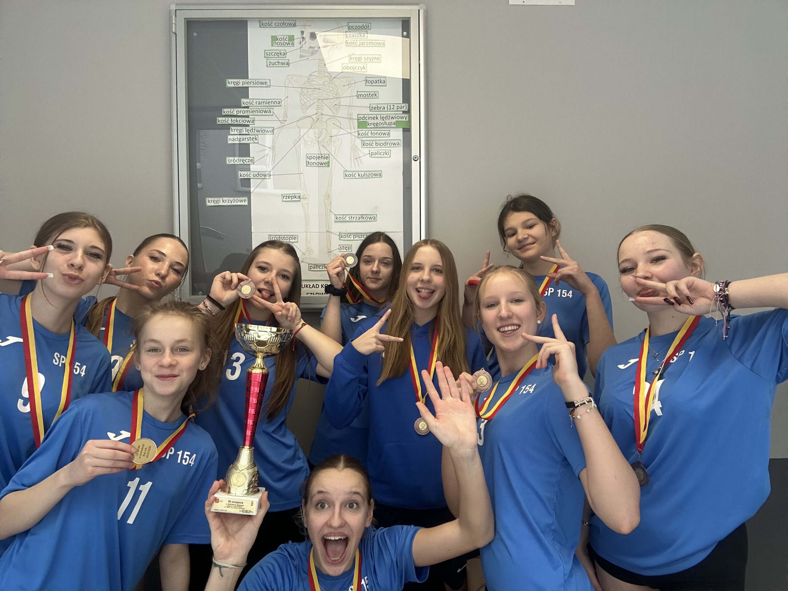 Dziewczyny pokazują brązowe medale i puchar z zawodów w unihokeju